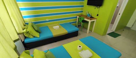 A room with two beds, a TV, a desk, and a chair.
