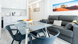 A modern living room with a glass dining table, grey sofa, and a painting of a desert landscape. - 101 Playa Honda, Playa de las Americas (Playa de las Américas)