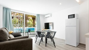 A modern living room with a sofa, a dining table with chairs, a flat-screen TV, and a white refrigerator. - 101 Playa Honda, Playa de las Americas (Playa de las Américas)