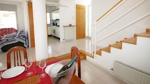A dining area with a table set for two, a bottle of champagne, and a view of a kitchen and staircase. - House for summer rental close to the beach.HUTG-071958 (l'Escala)