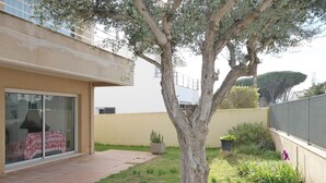 A residential garden with a large tree, a patio area, and a building with a sliding glass door. - House for summer rental close to the beach.HUTG-071958 (l'Escala)