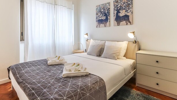 Una habitación de hotel con una cama, dos mesitas de noche, un aparador y dos obras de arte en la pared.