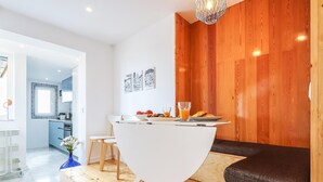Un espace repas moderne avec une table blanche, un plancher en bois et un mur décoratif en bois.