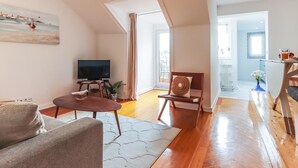Un salon moderne avec un téléviseur à écran plat, un canapé, une table basse et un tableau accroché au mur.