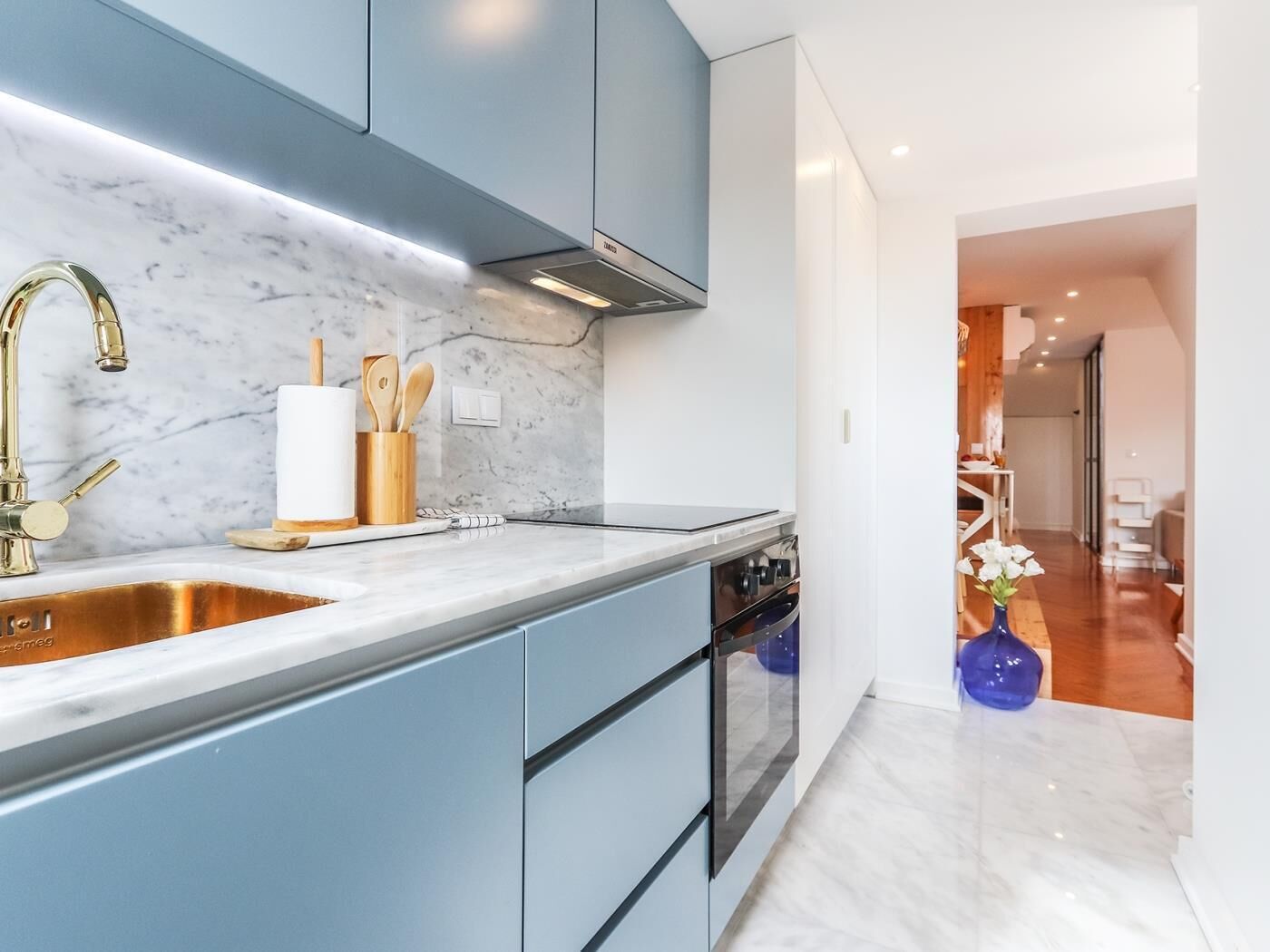 A modern kitchen with a marble countertop, stainless steel sink, and built-in oven.