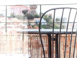 A balcony with a metal chair and table, overlooking a cityscape with buildings and a tower. - Vita Portucale | Almirante Panoramic View (Lisboa)