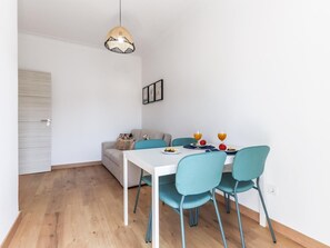 Uma sala de jantar com uma mesa branca, cadeiras azul-turquesa e um lustre.