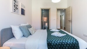 Ein Hotelzimmer mit Bett, Nachttisch, Spiegel und einer Tür zu einem Badezimmer.