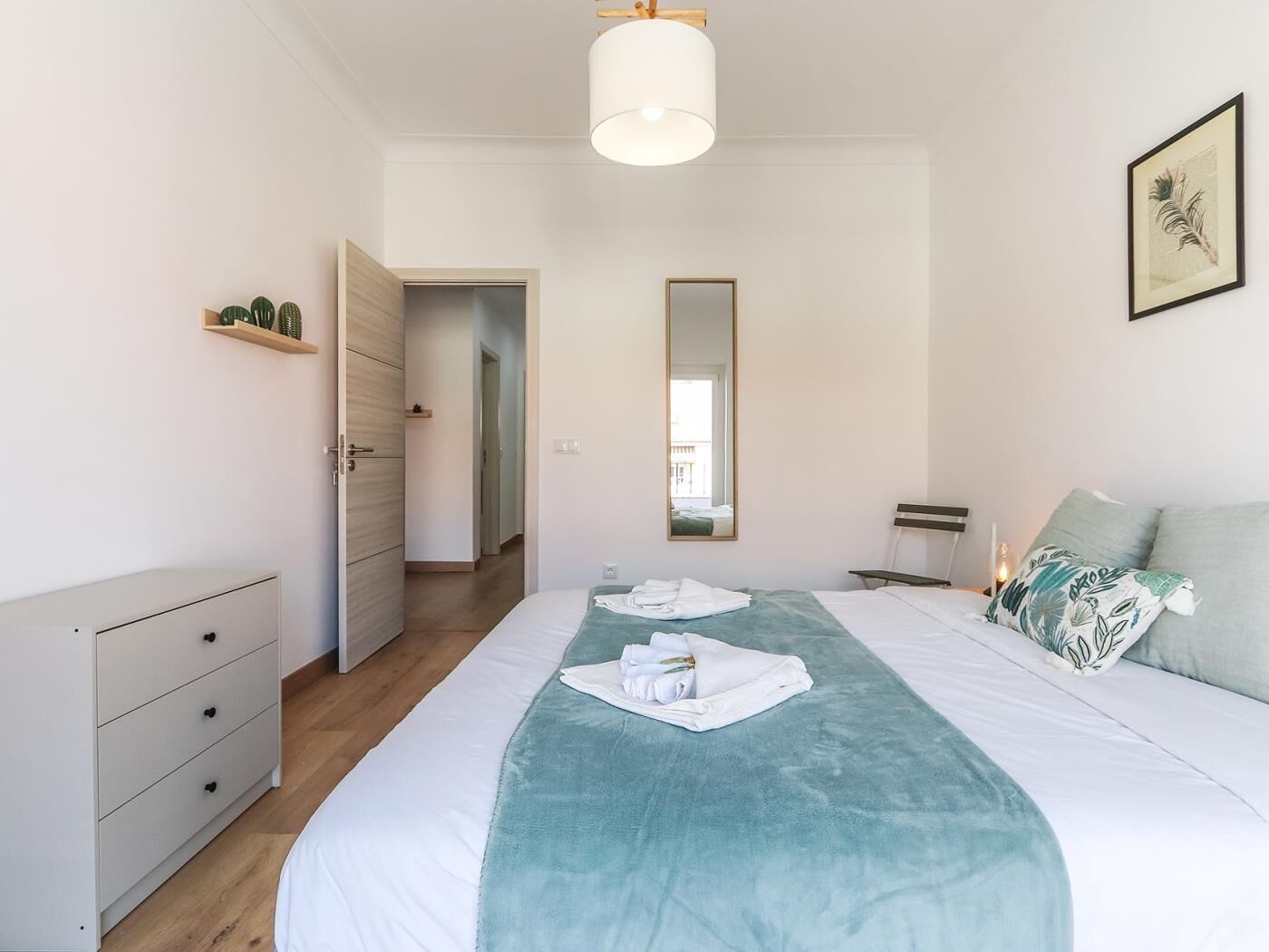 Une chambre à coucher comprenant un lit, une table de chevet, un miroir et une porte donnant sur une autre pièce.
