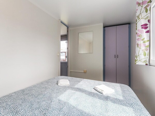 A bedroom with a bed, a door, and a window with curtains.