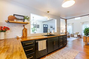 A modern kitchen with a wooden countertop, black cabinets, and a large window. - Our Peaceful Haven - 6 minutes to Trilith Studios (Fayetteville)