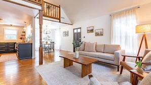 A spacious living area with a wooden coffee table, a sofa, and a dining table with chairs. A staircase leads to an upper level. - Our Peaceful Haven - 6 minutes to Trilith Studios (Fayetteville)