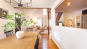 A modern kitchen with stainless steel appliances, a wooden dining table, and a staircase leading to an upper level. - Our Peaceful Haven - 6 minutes to Trilith Studios (Fayetteville)