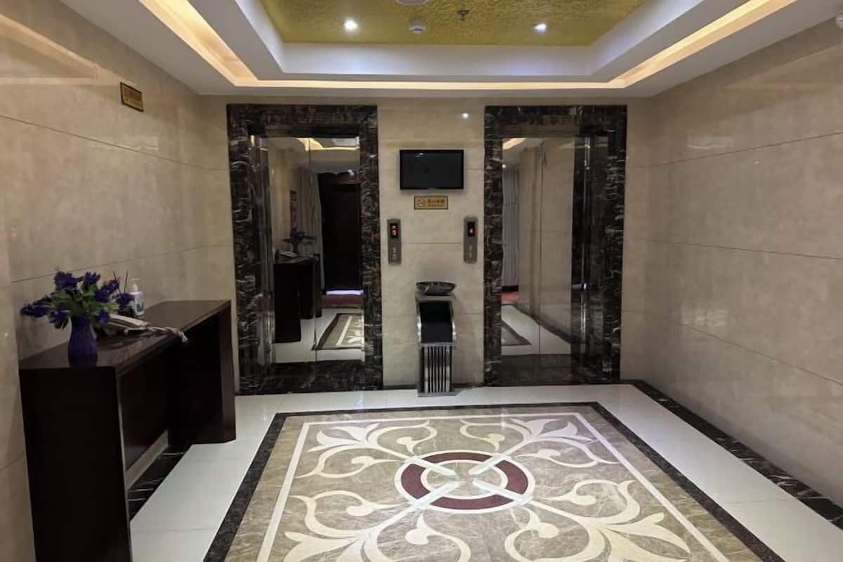 Un vestíbulo de hotel con piso de mármol, un mostrador de recepción y un diseño de techo moderno.