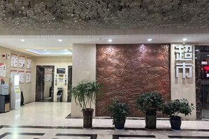 A hotel lobby with a decorative wall, potted plants, and a reception area. - Chunguang Hotel (Xiji)