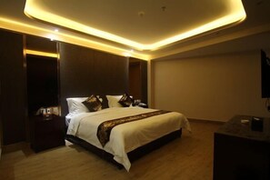 A modern hotel room with a large bed, dark wood flooring, and a ceiling with recessed lighting. - Chunguang Hotel (Xiji)