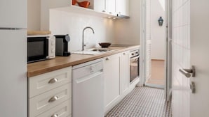 A compact kitchen with white cabinets, a microwave, a coffee maker, a sink, and a dishwasher. - Dona Ana by Interhome (Lagos)