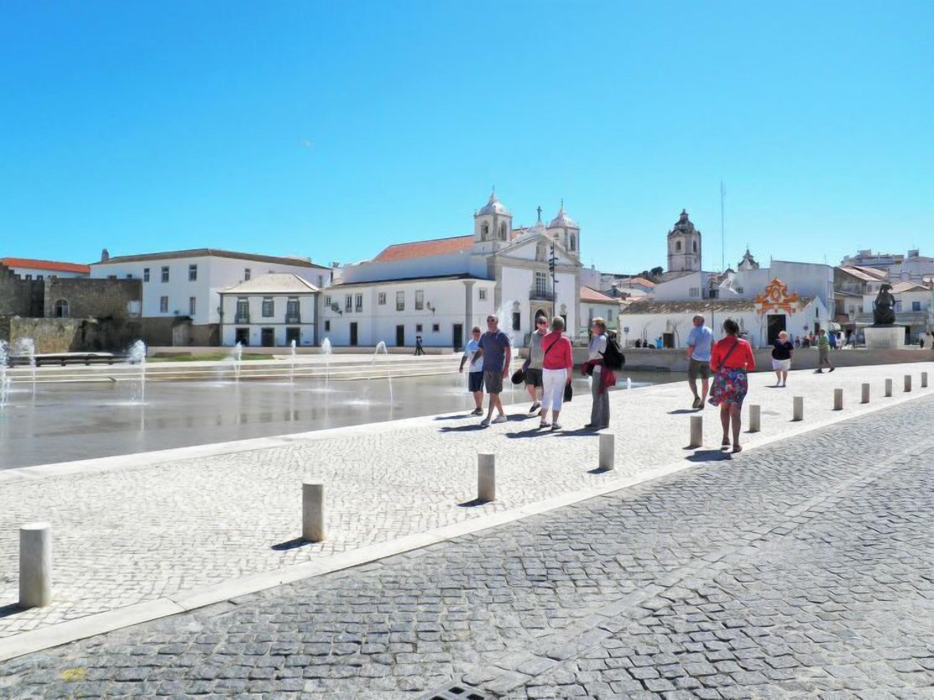 A cobblestone pathway with a fountain and historic buildings in the background.