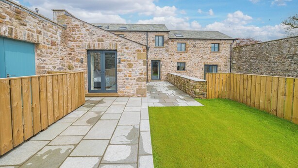 A stone building with a paved patio and a grassy area. - No 2 The Coach House (Carnforth)
