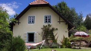 Une maison à deux étages, dotée d’un toit en pente, d’une porte d’entrée et d’un petit porche surmonté d’un auvent à rayures rouges et blanches.