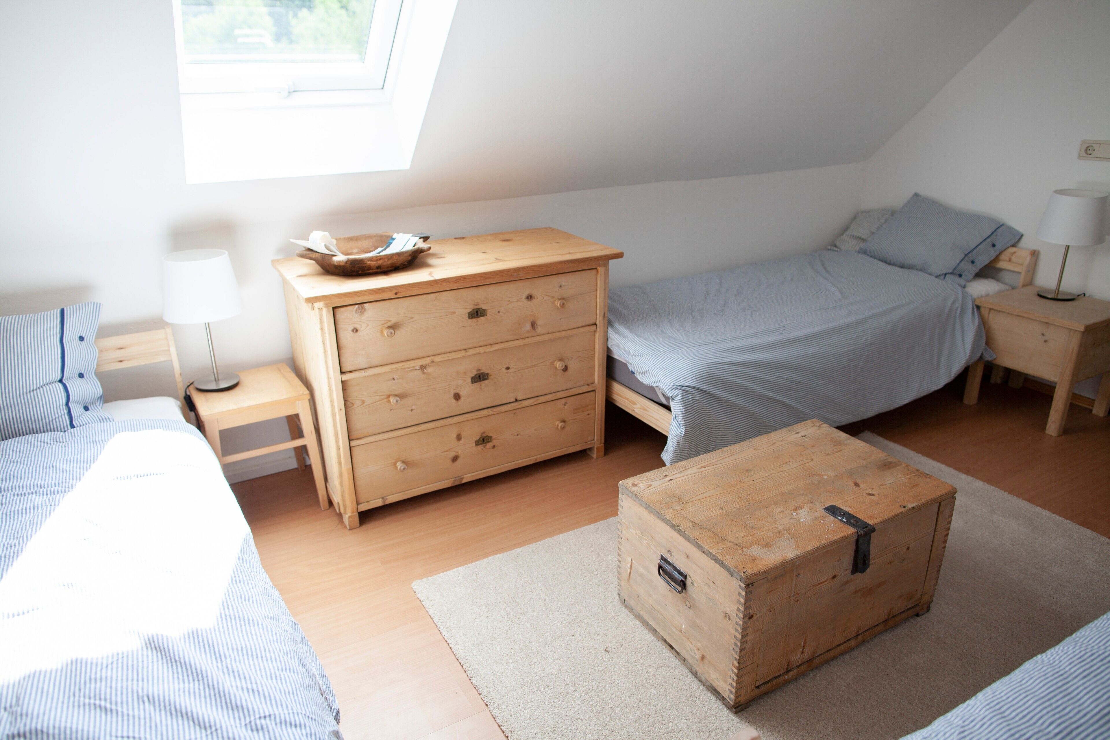 Une chambre à coucher comprenant un lit, une commode en bois, une coiffeuse et une table de chevet.