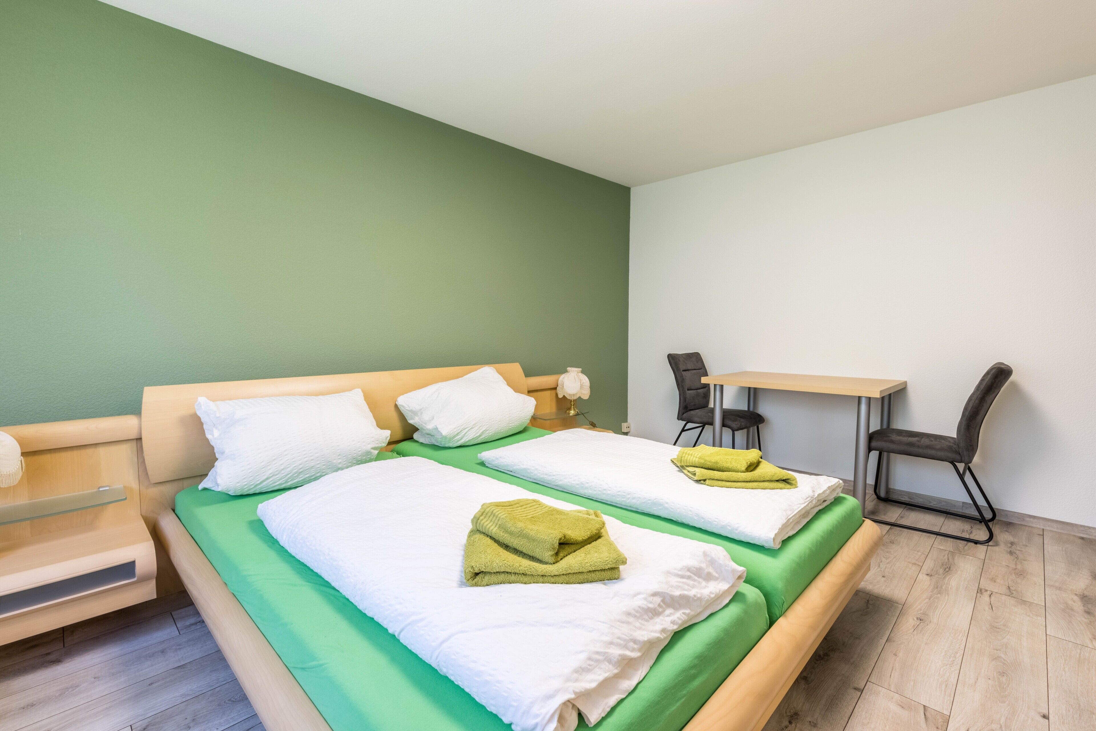 Een kamer met twee bedden, een bureau en een stoel.
