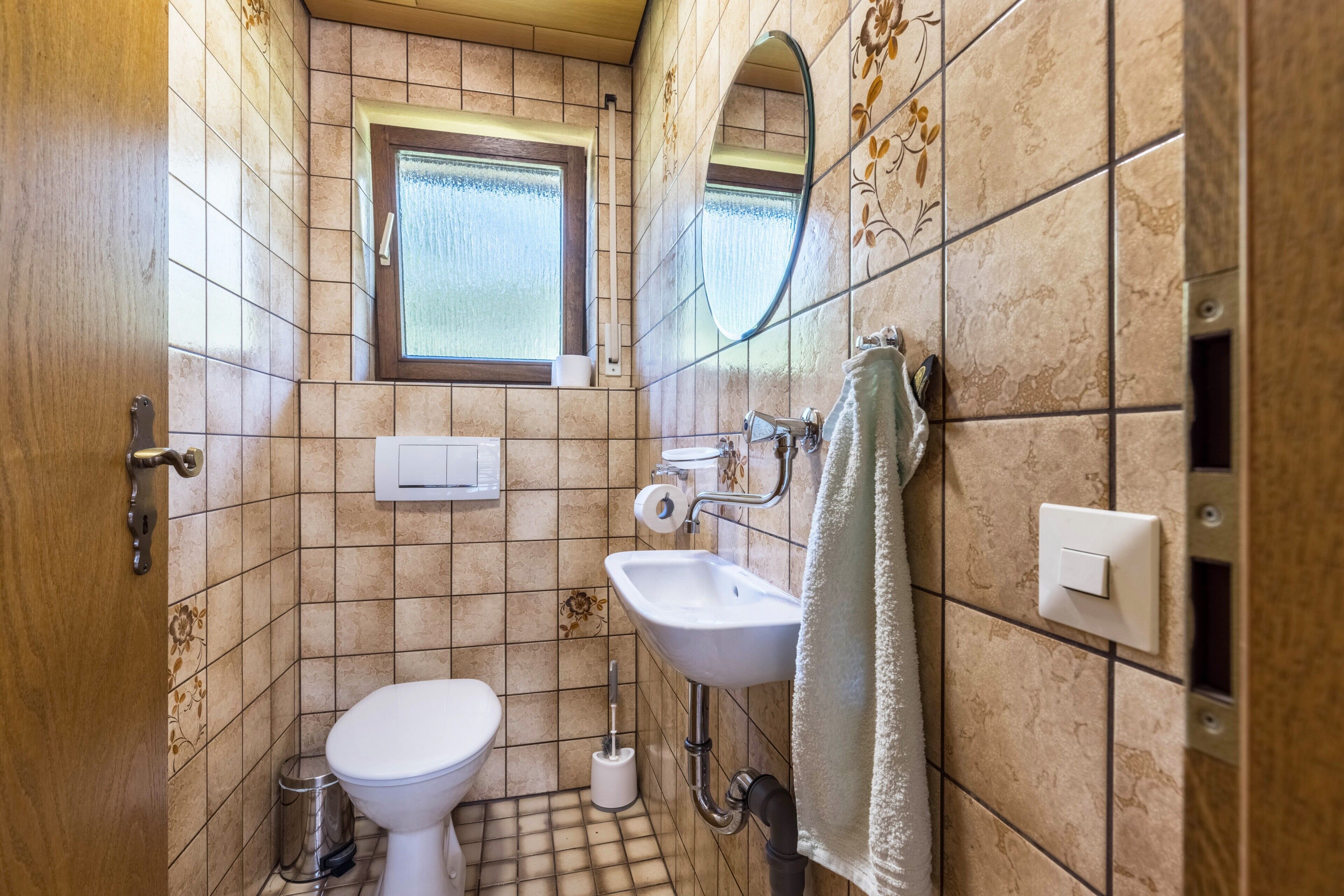 A small bathroom with a toilet, sink, and window.