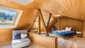 Un interior de madera con cama, sofá y tragaluz.