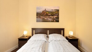 Una camera d'albergo con un letto, due comodini con lampade e un quadro raffigurante un paesaggio sulla parete.