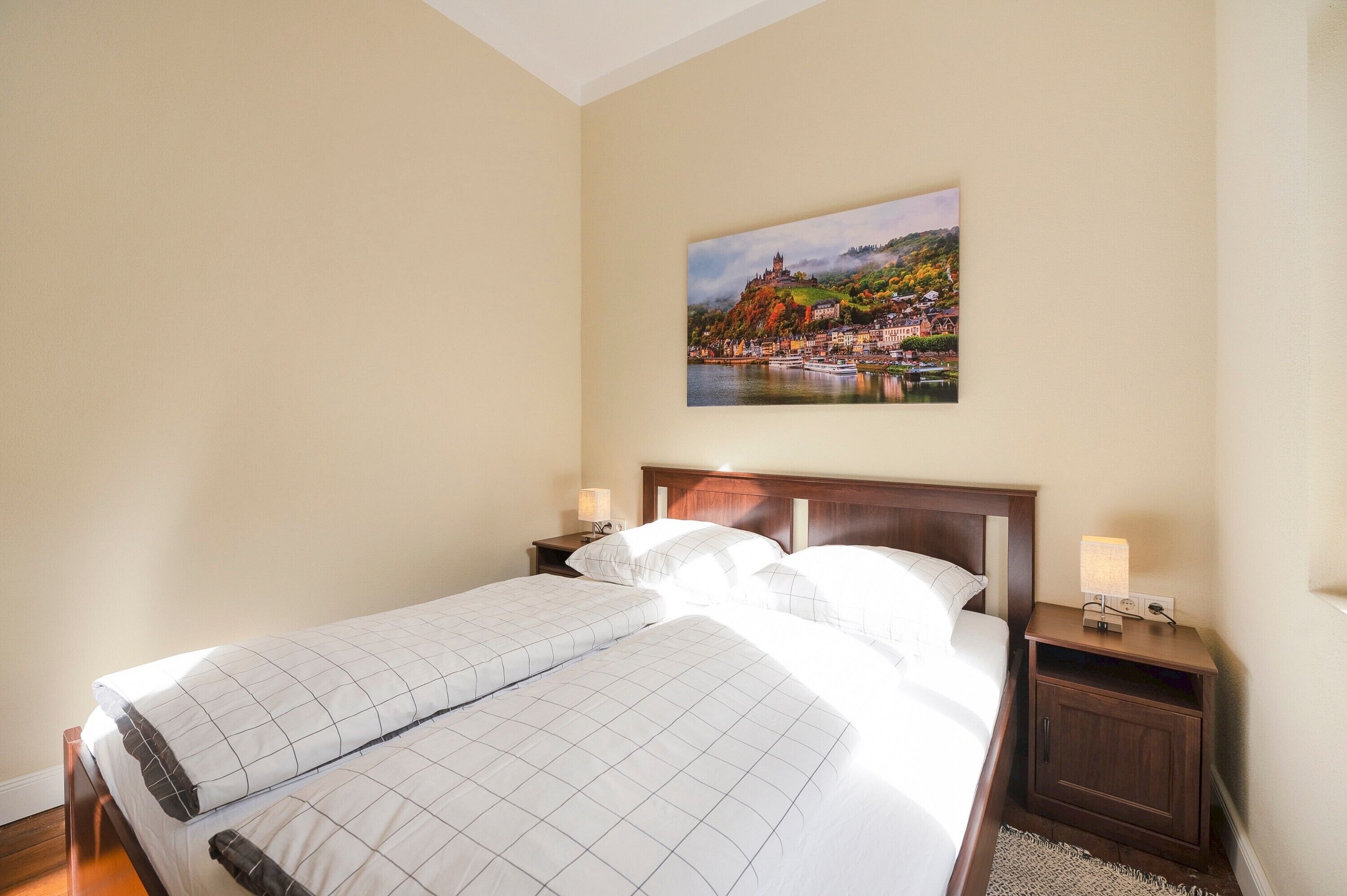 Ein Hotelzimmer mit einem großen Bett, zwei Nachttischen und einem Wandbild mit einer schönen Landschaft.