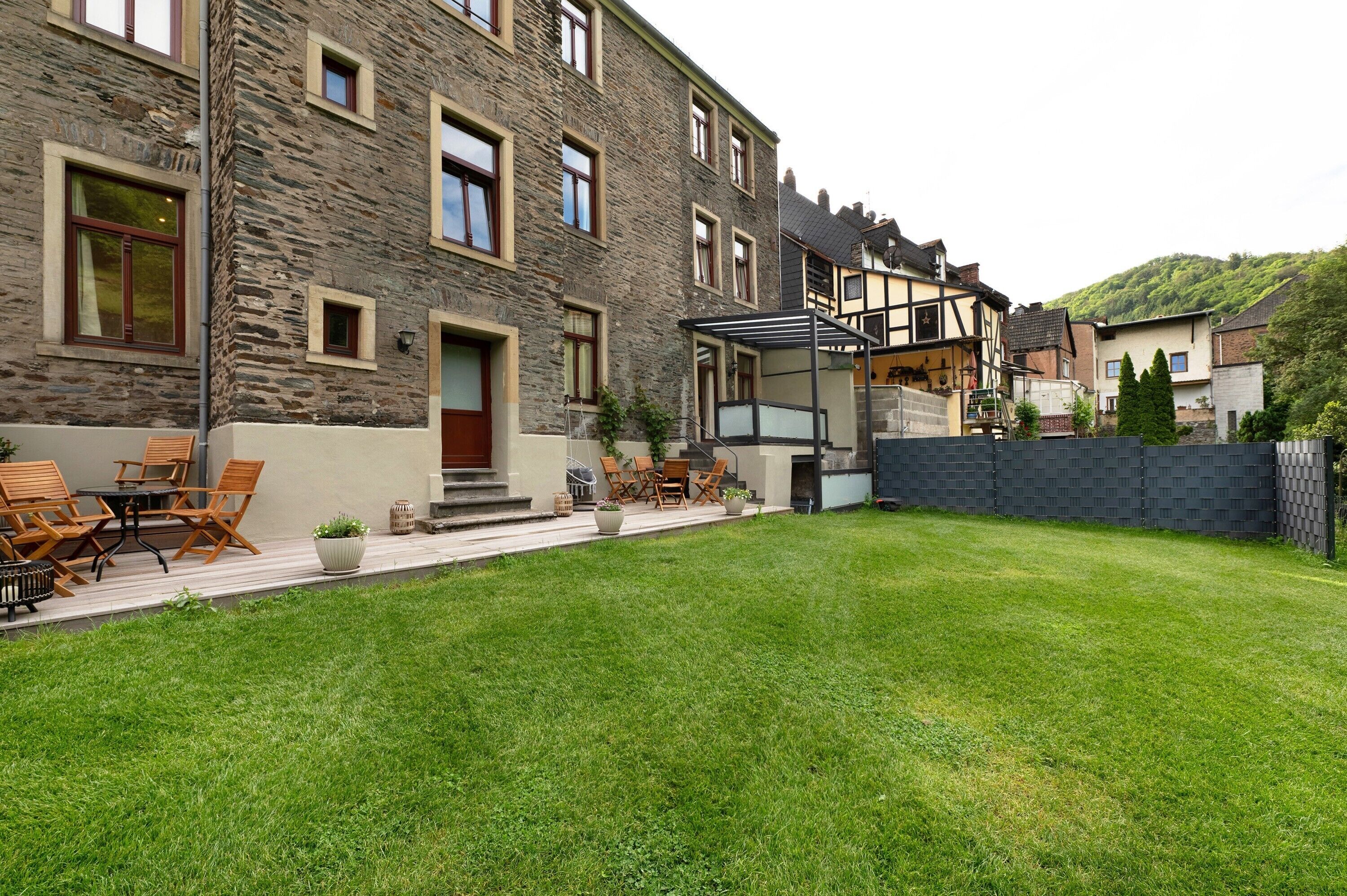 A stone building with a patio, outdoor seating, and a view of a hill.