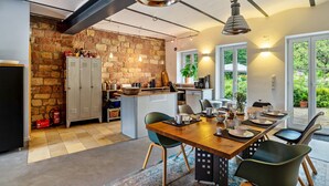 Una cocina moderna con pared de piedra, armarios de madera y un comedor con mesa preparada para cuatro.