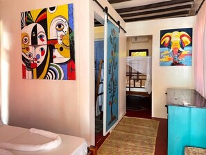 A room with a bed, a blue cabinet, and two paintings on the walls.