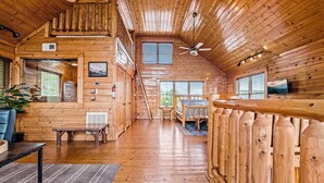 Een ruime houten chalet met een slaapkamer op de entresol, een eethoek en een woonkamer.