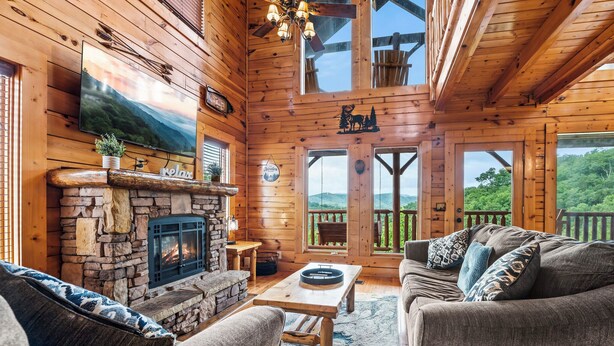 Een gezellig chaletinterieur met een stenen open haard, houten wanden en een grote televisie.