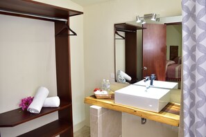 A bathroom with a wooden vanity, a large mirror, and a towel rack.