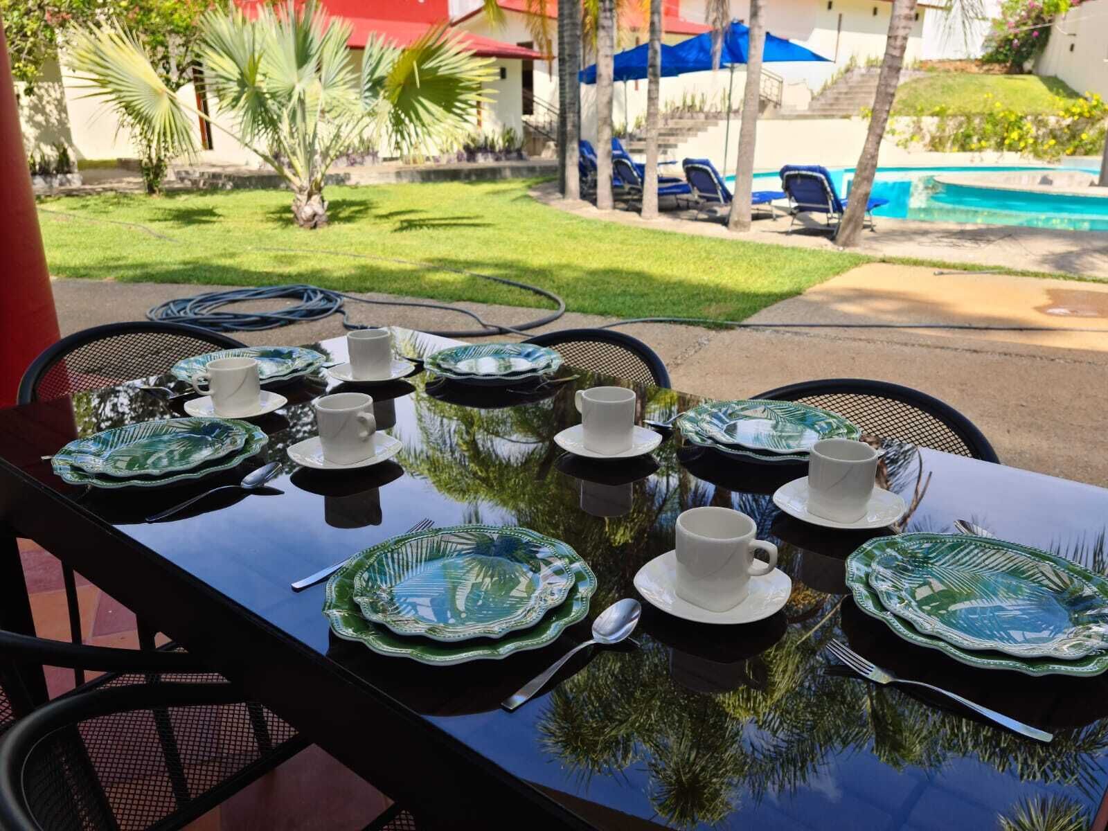A table set for a meal with green and white plates, white cups, and cutlery.