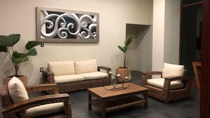 A living room with a sofa, two wicker chairs, a coffee table, and a decorative wall piece. - Santa Clara Hotel Campestre (San Juan Bautista Tuxtepec)