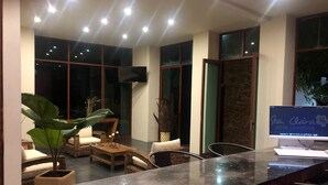 A modern hotel lobby with a reception desk, comfortable seating, large windows, and a flat-screen TV. - Santa Clara Hotel Campestre (San Juan Bautista Tuxtepec)