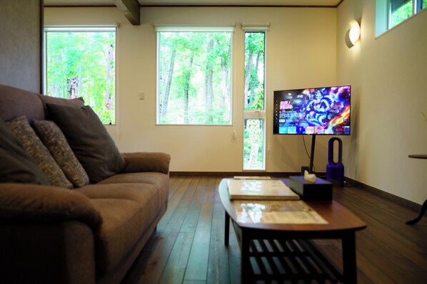 A living room with a brown sofa, a wooden coffee table, and a flat-screen TV on a stand. - BETSUINN MINI (Hakuba)