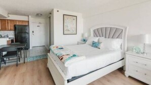 Un dormitorio con cama, mesita de noche y un pequeño escritorio con una silla.