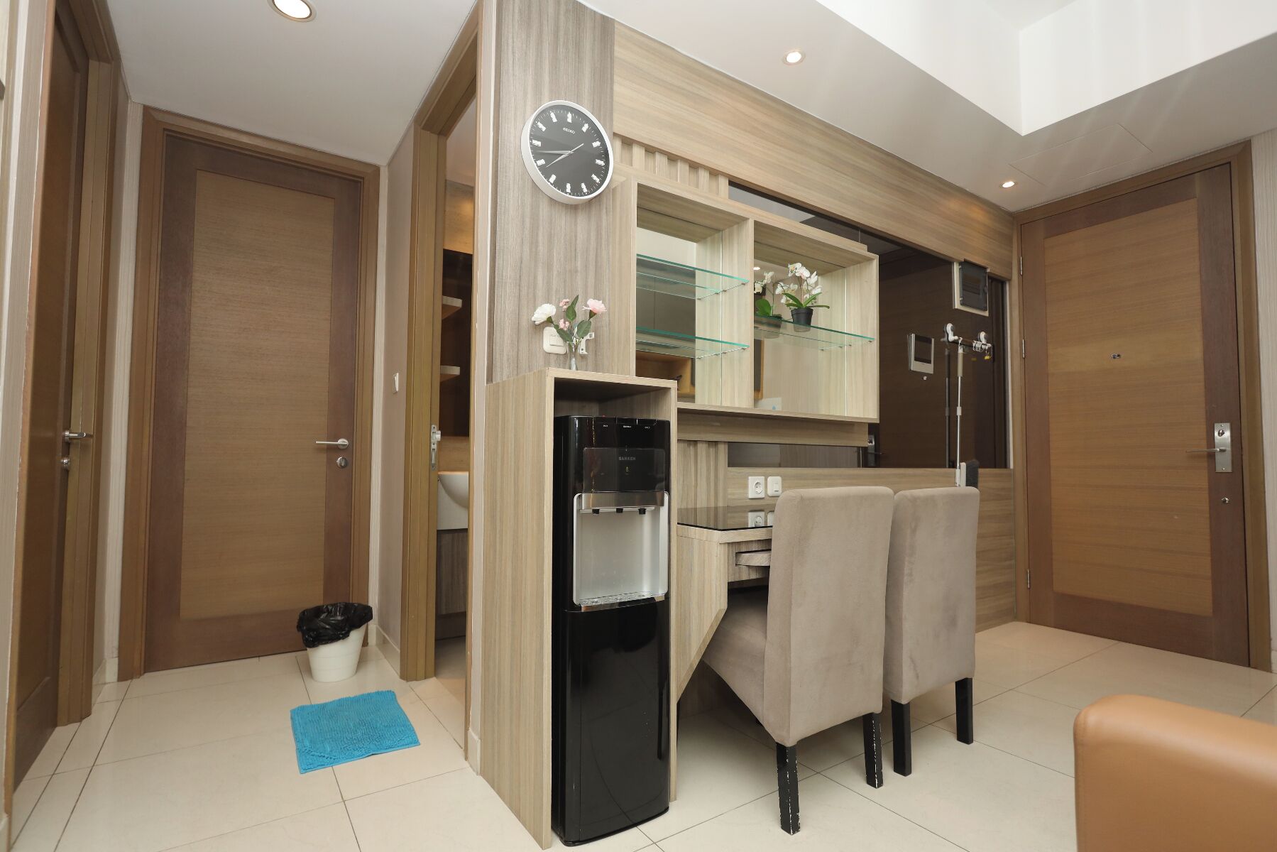 Una cocina moderna con refrigerador empotrado, un reloj y un comedor con sillas.