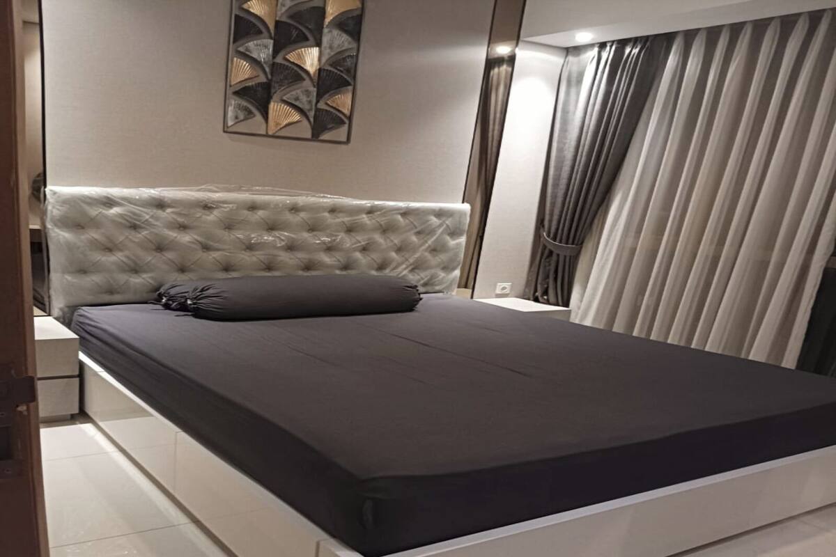 A modern bedroom with a tufted headboard, a large bed, and a minimalist design.
