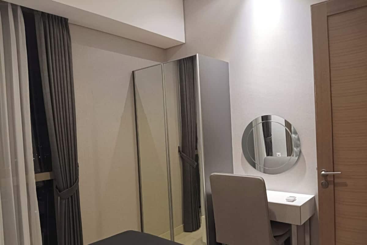A modern room with a dark-colored table, a white chair, a round mirror, and a wardrobe with a mirror.