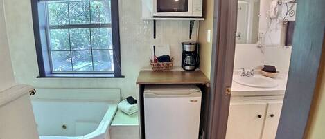 Cozinha compacta com micro-ondas, cafeteira e pequena geladeira.