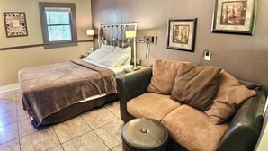 A hotel room with two beds, a sofa, a trash bin, and framed pictures on the walls. - D'vinery Rock Cottage/ #6 (Eureka Springs)