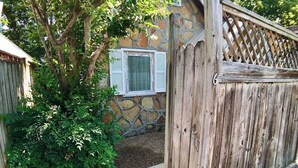 A stone building with a wooden fence and a window with shutters. - D'vinery Rock Cottage/ #6 (Eureka Springs)