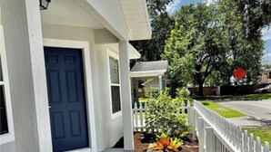 A house with a blue door, a white porch, and a garden with plants. - Downtown Orlando Creative Oasis- Hand Painted Murals & Free Parking.  (Orlando)