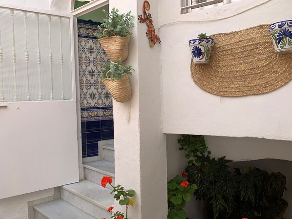 A staircase with white steps leading to a door, a wall with a blue and white patterned tile, and a woven basket hanging on the wall. - Casa Ana in Vejerde la Frontera (Vejer de la Frontera)