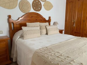 A neatly made bed with a wooden headboard, multiple pillows, and a bedside table with a lamp. - Casa Ana in Vejerde la Frontera (Vejer de la Frontera)